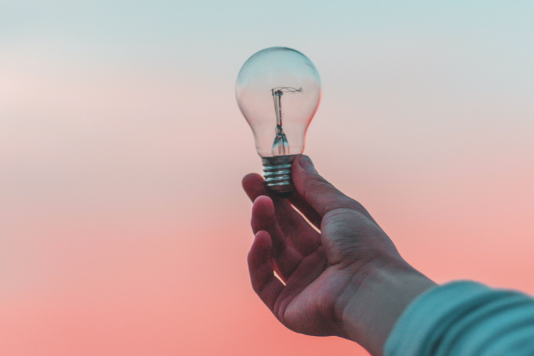 A hand holding a light bulb