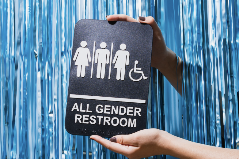 Sign saying all gender restroom in front of blue tinsel